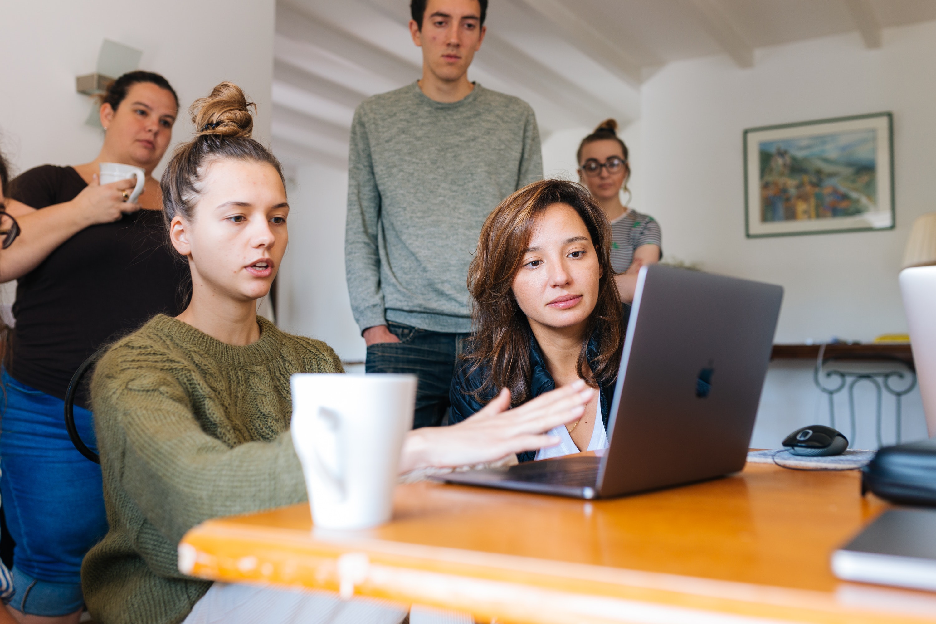 woman-in-green-top-using-macbook-beside-group-of-people-1595392